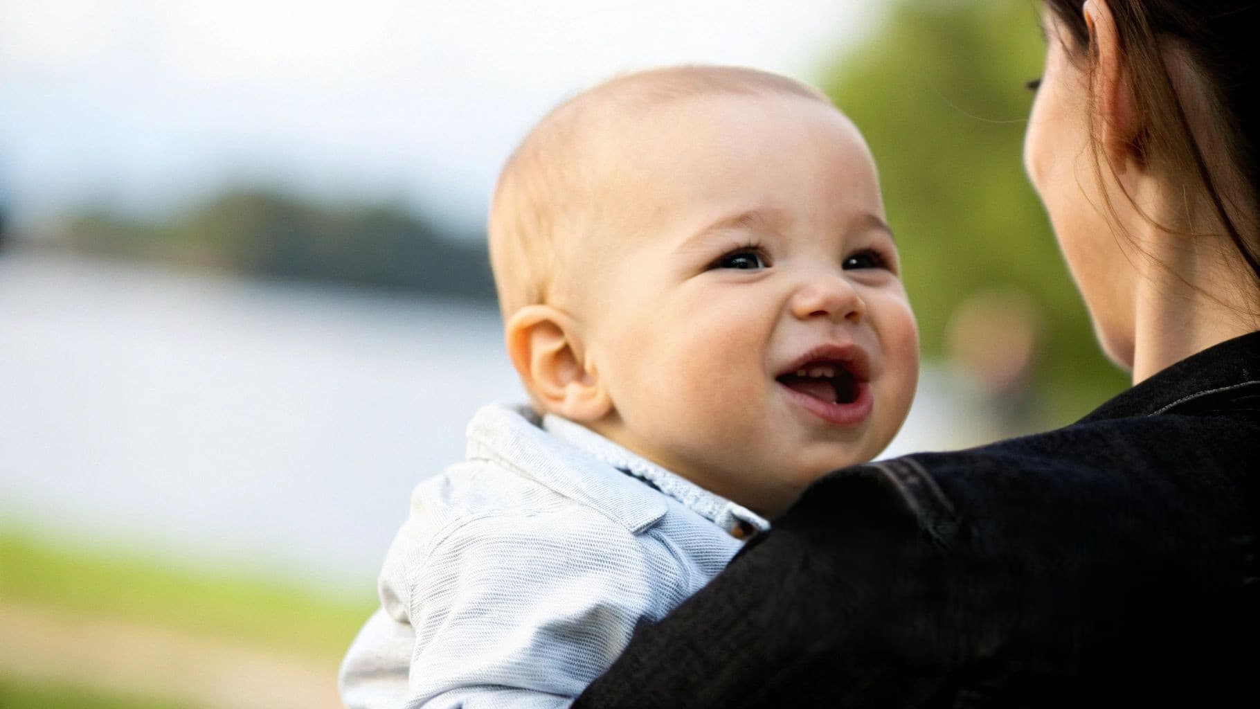 Un bébé souriant aux yeux brillants, porté par une femme, avec le texte "Poussée Dentaire".
